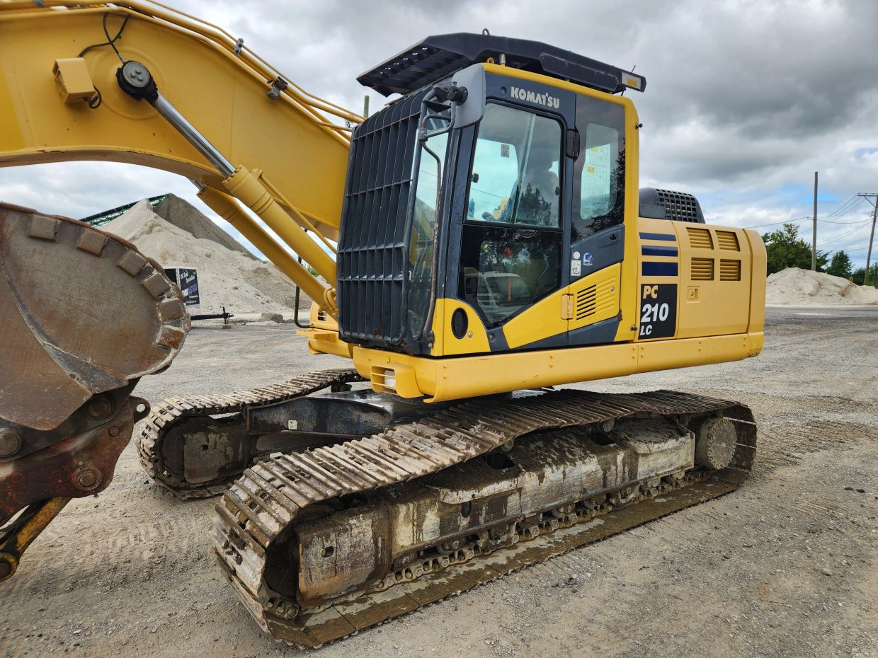 Yellow Komatsu PC 210 LC excavator on a construction site.