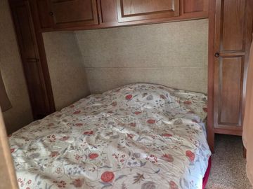 Cozy bed with floral bedding in a wooden framed room.