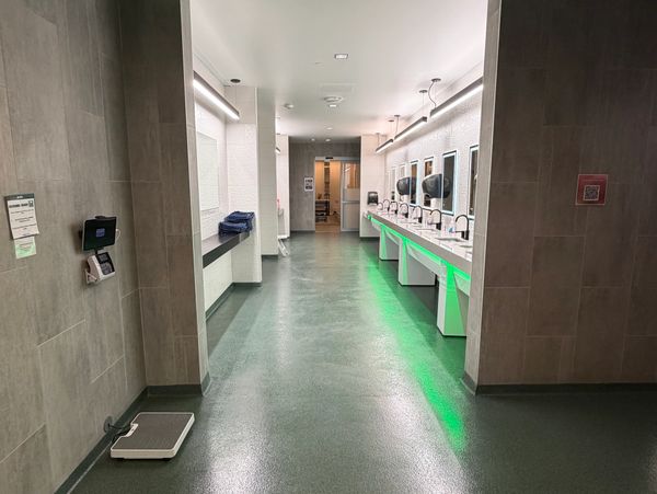 Modern public restroom with green lighting and multiple sinks.