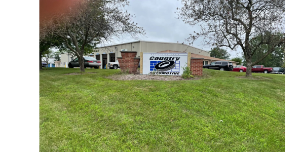 Country Automotive building with sign and cars parked outside on a cloudy day.