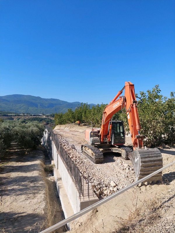 Bir kazıcı inşaat alanında toprak içinde çalışıyor.