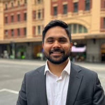 Man in a suit smiling outdoors.