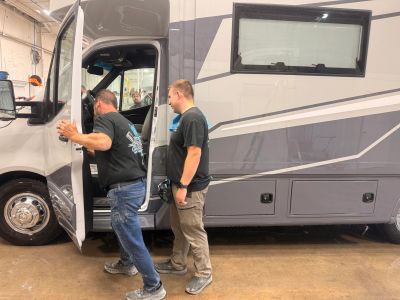 Two men inspecting an RV indoors.
