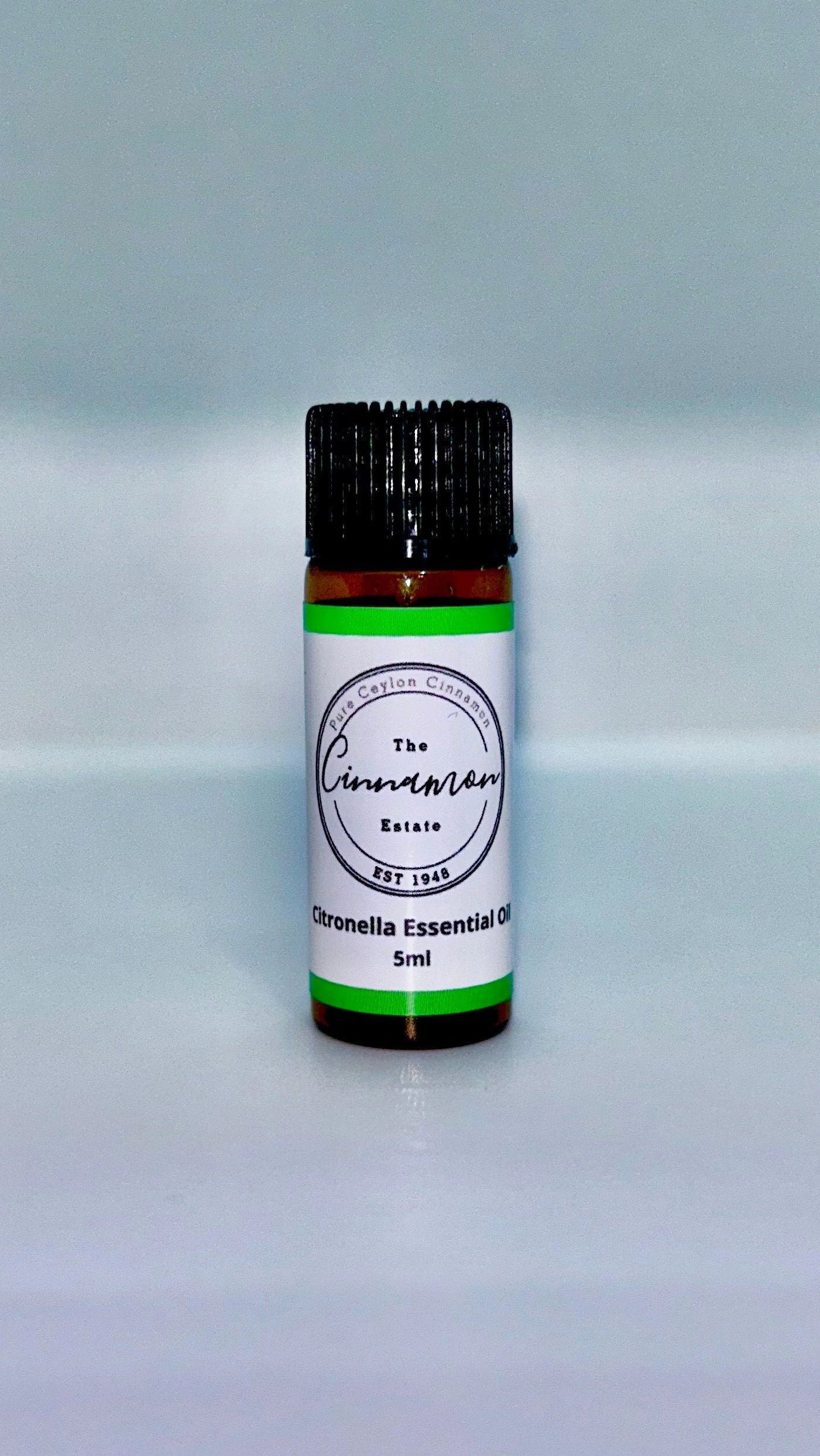 An amber dropper bottle of The Cinnamon Estate citronella essential oil, with a bright green striped label.