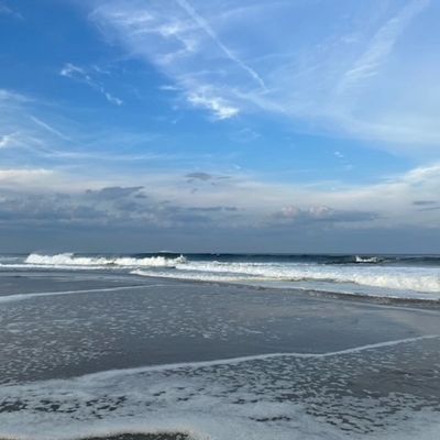 a beach with waves and a cloudy sky