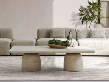 Modern travertine coffee table with sculptural stone legs in a minimalist living room
