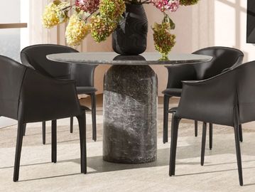 round marble dining table with sculptural stone base in a modern interior setting