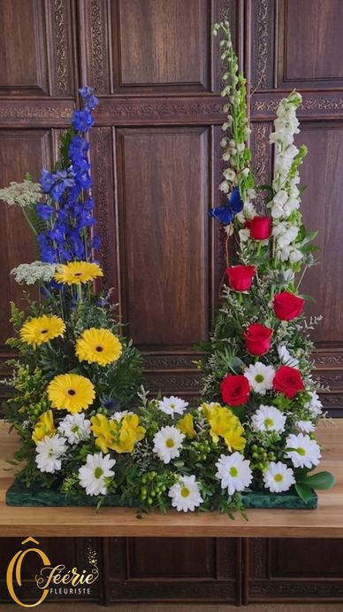 Composition florale colorée avec roses rouges, marguerites blanches et fleurs jaunes.