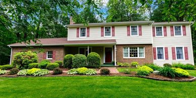 Two-story suburban house with a well-maintained garden and lush green lawn.