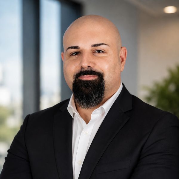 Confident bald man with a beard in a black suit and white shirt.