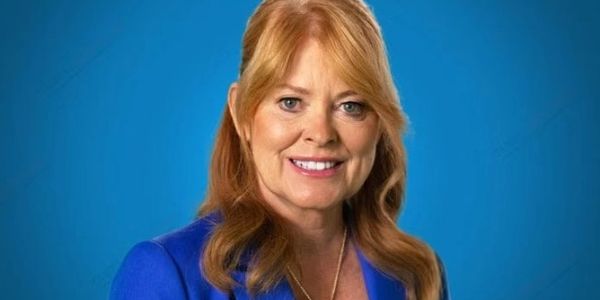 Smiling woman with red hair in blue blazer.