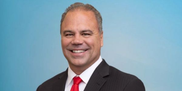 Smiling man in suit and red tie on blue background.