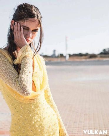 Young woman in yellow dress posing outdoors.