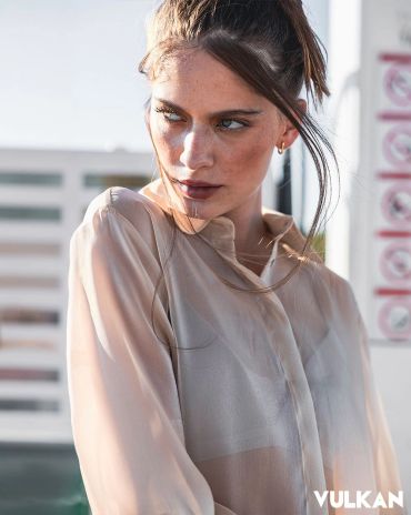 Woman in sheer blouse looking sideways.