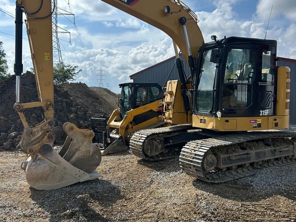 Two yellow excavators parked on gravel.