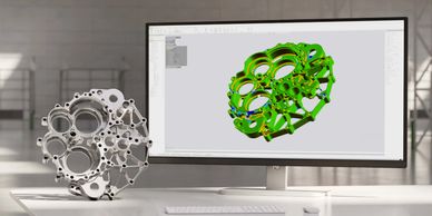Modelo 3D y pieza mecánica en escritorio de trabajo.