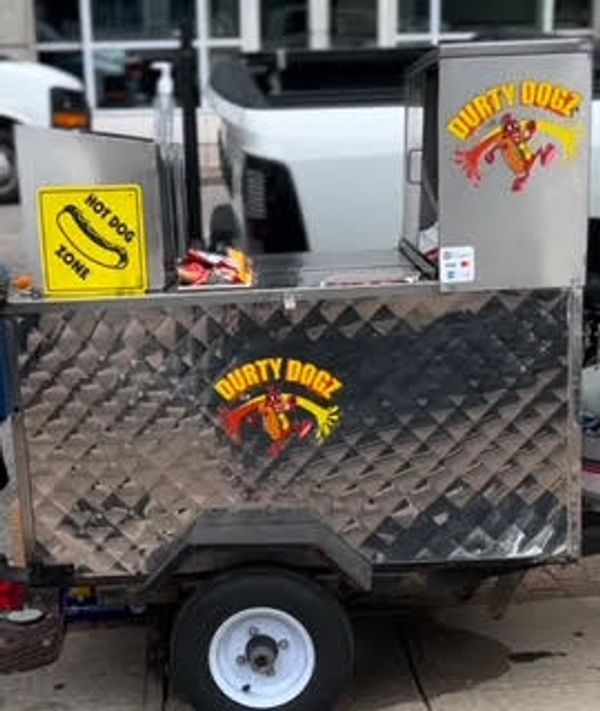 Durty Dogz hot dog street cart with bright signage on a city sidewalk.