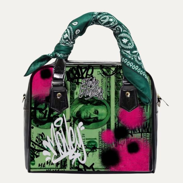 Fashion handbag with dollar bill print and graffiti art, featuring a green bandana on the handle.