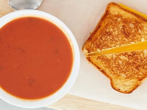 Classic tomato soup with grilled cheese sandwich on a wooden board.