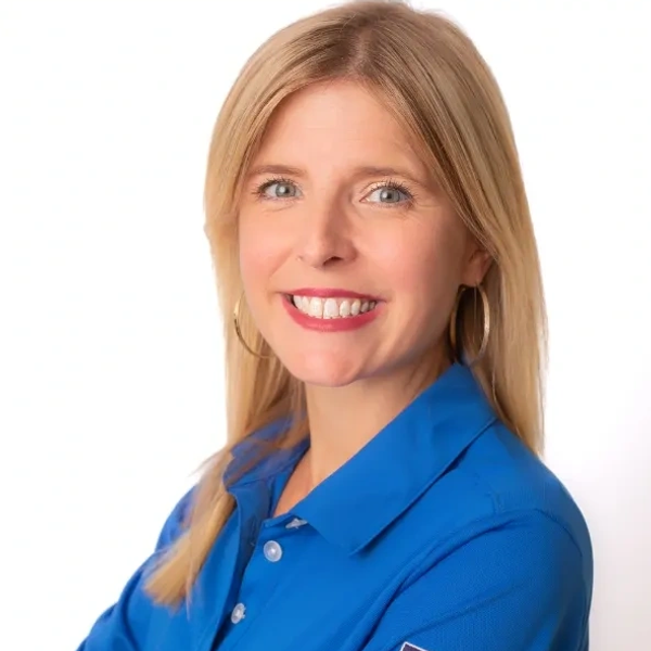 Smiling woman in blue shirt with hoop earrings.