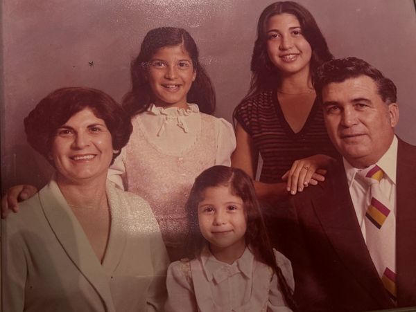 A vintage family portrait with parents and three daughters smiling.