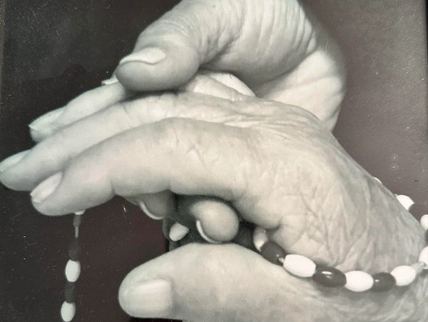 Close-up of elderly hands holding a beaded bracelet.