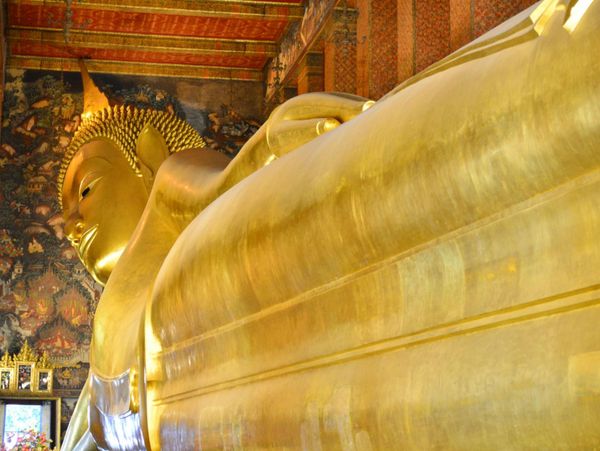 Golden Reclining Buddha statue inside a temple with ornate decorations.