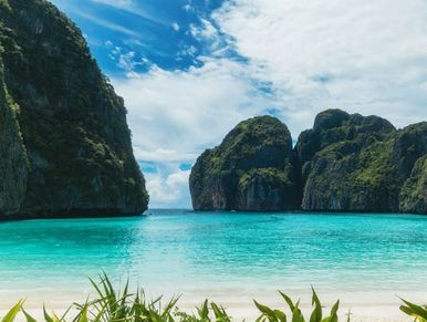 Turquoise sea with rocky islands under a partly cloudy sky.