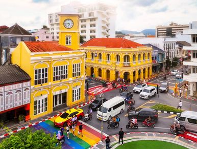 Colorful historic buildings with a clock tower at a busy intersection.
