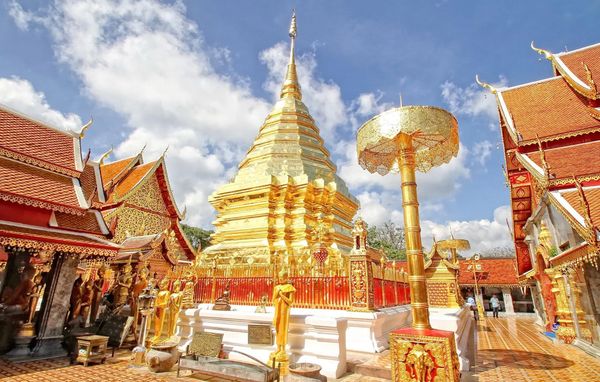 Golden Buddhist temple under a bright blue sky.