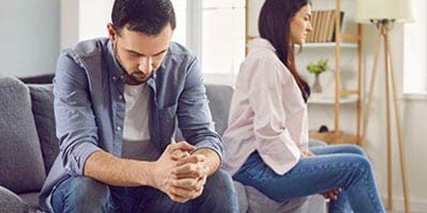 A couple sitting apart, looking upset after a disagreement.