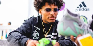 Young man with glasses holding green sneakers.