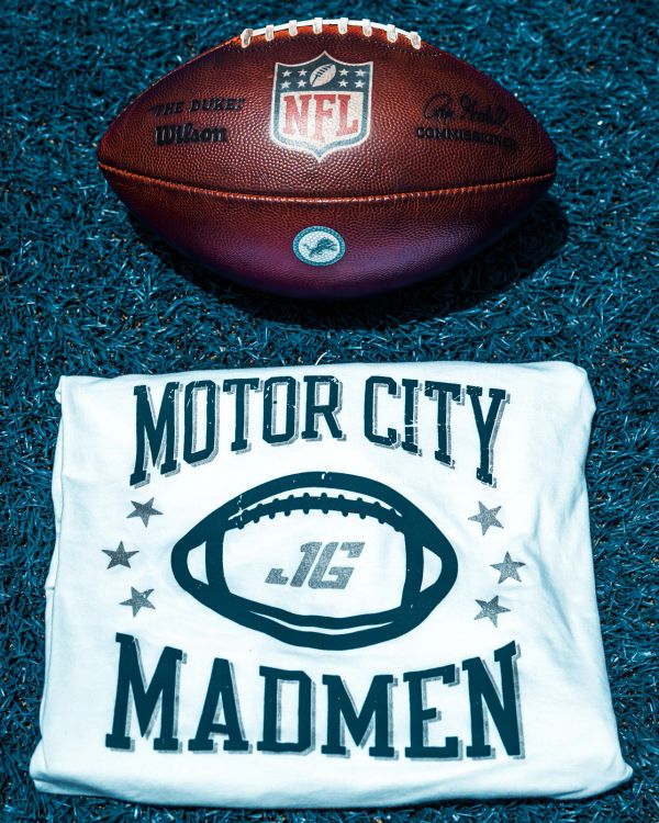 NFL football and Motor City Madmen shirt on turf.