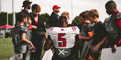 Football players and coach huddle on the field.