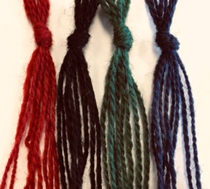 Four colorful yarn tassels in red, black, green, and blue.