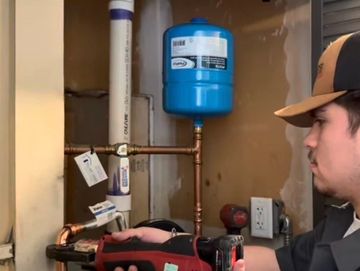 Technician inspecting a plumbing system with a pressure tank.