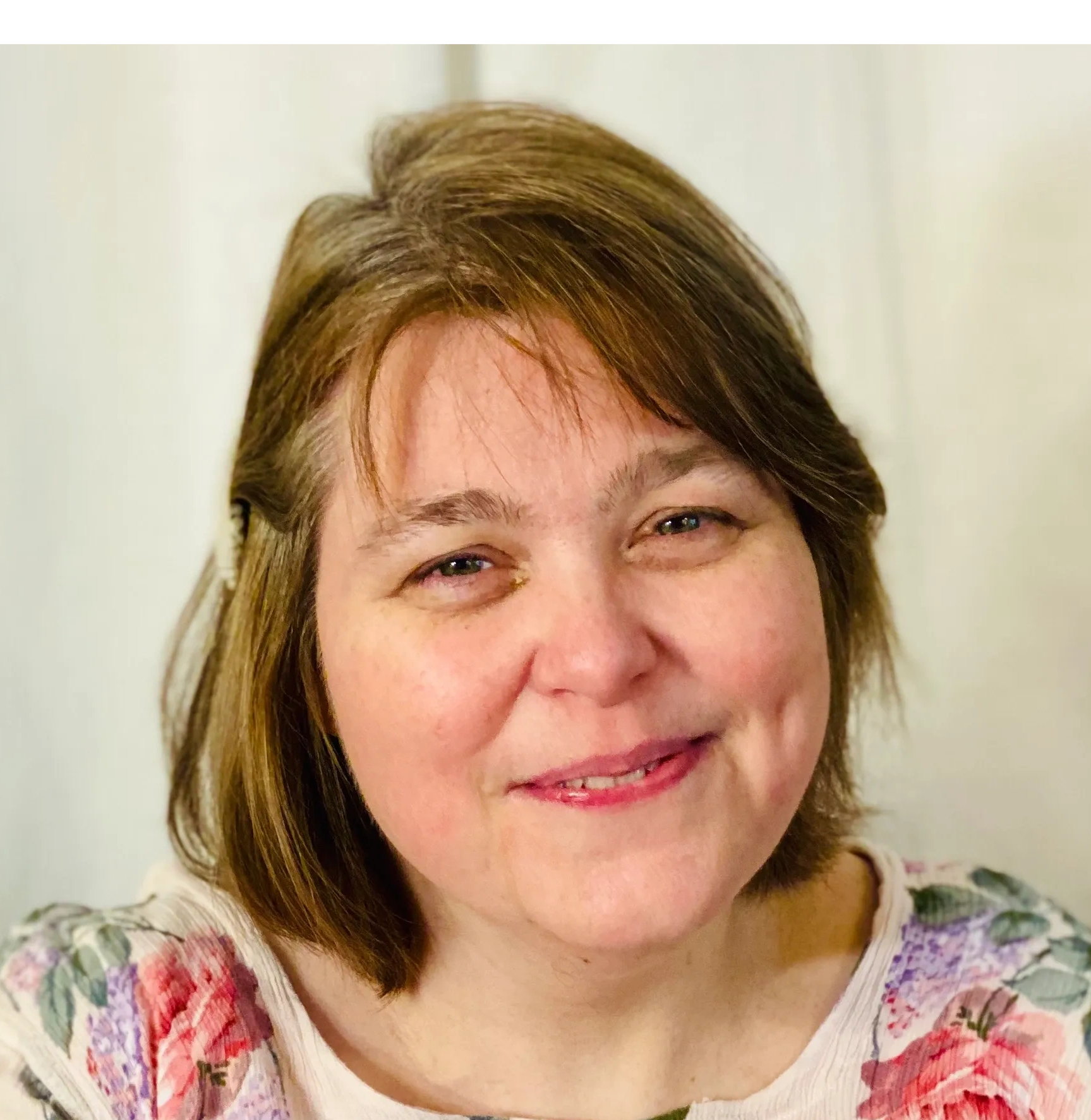 Lara Minges is pictured wearing a floral top with her light brown hair pinned back on one side. She 