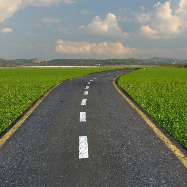 A winding road labeled 'SUCCESS' stretches through green fields under a partly cloudy sky.