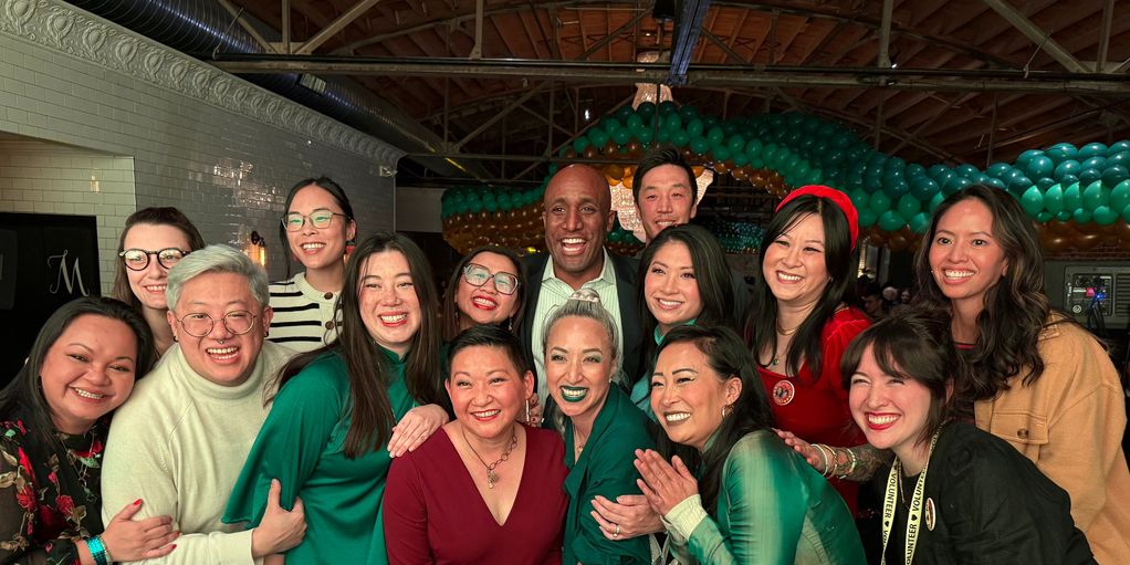 A joyful group of diverse friends posing together indoors with smiles and colorful attire.