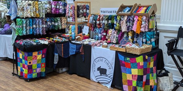 Colourful yarn display at a craft market stall named Wild Field Fibre.