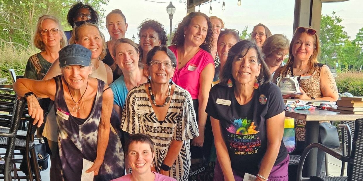 Group of smiling women posing together outdoors.