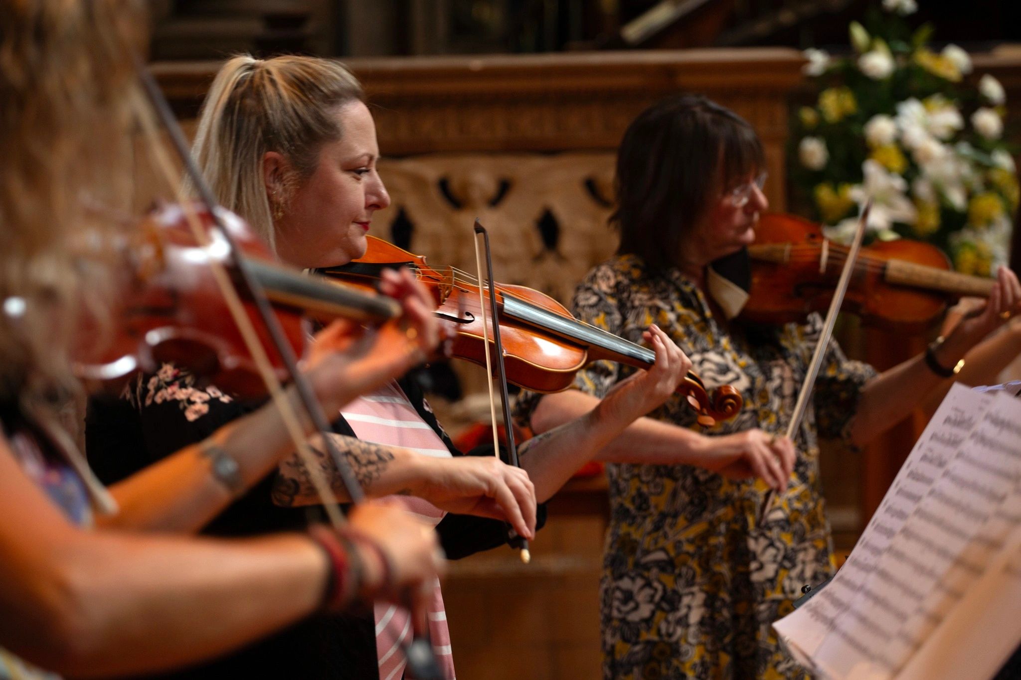 Women playing violins in a music ensemble.