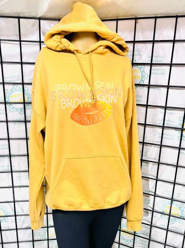 Yellow hoodie with 'BROWN SKIN' text and lip graphic on display.