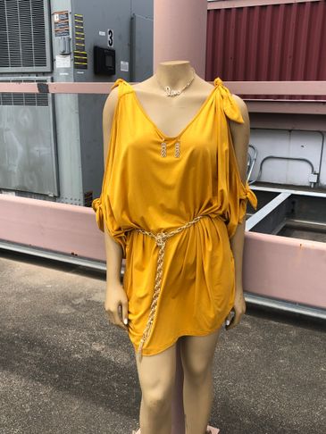 Mannequin wearing a stylish mustard yellow dress with a chain belt and necklace.