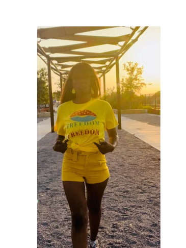 Woman in yellow outfit walks confidently at sunset in a park.