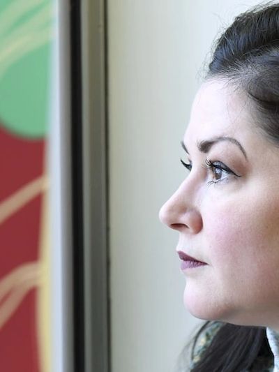 A side profile of Crystal gazing out a window, she appears reflective. 