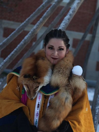 Crystal dressed in Dinjii Zhuh ceremonial dress, smiling at the camera against a winter backdrop.