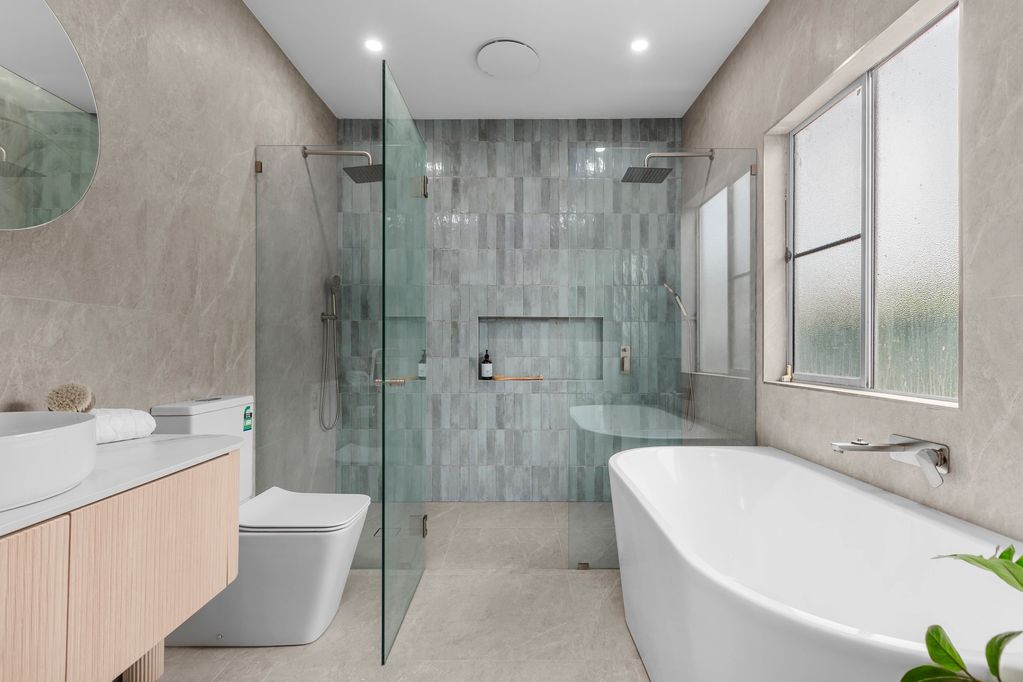 A modern bathroom with a freestanding tub and glass-enclosed dual shower.