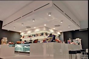Modern café counter with drinks and snacks under bright ceiling lights.
