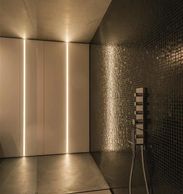 Modern bathroom with sleek lighting and dark mosaic tiles.